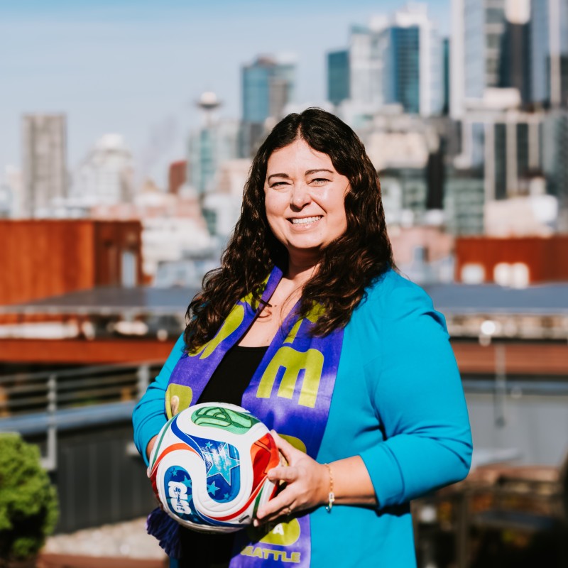 Mikaela Purvis holds a soccer ball in front of the Seattle skyline
